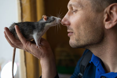 Close-up of man holding a cute mouse at home