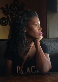 Portrait of woman looking away while sitting on table