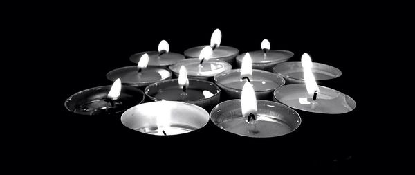 Close-up of lit candle over black background