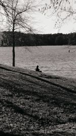 Silhouette man on riverbank against sky