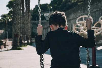 Rear view of boy swinging at playground