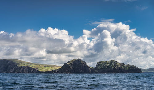 Majestic and tall kerry cliffs with fields on the top, seen from a boat on atlantic ocean, ireland