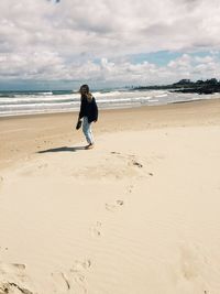 Full length of man standing on beach against sky