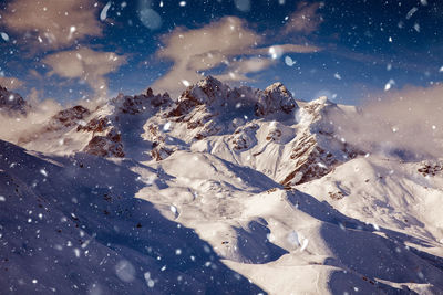 Scenic view of snowcapped mountains during snowfall