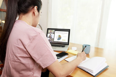 Midsection of man using mobile phone while sitting on table