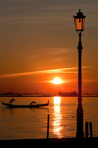 Silhouette people on boat sailing in river at sunset