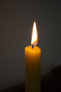 Close-up of burning candle against black background