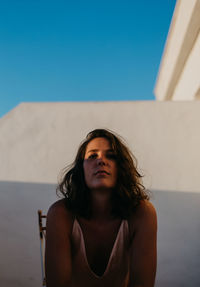 Portrait of young woman against blue sky