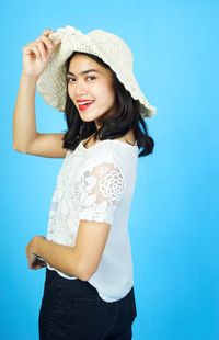 Portrait of a smiling young woman standing against blue sky