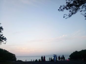 Silhouette people on beach against sky during sunset