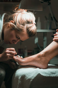 Woman doing pedicure of customer in parlor