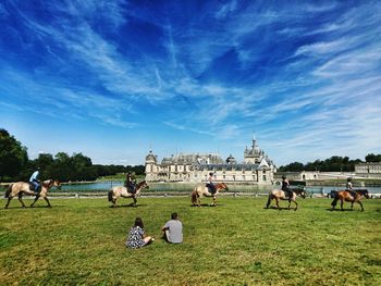 Couple looking at people riding horses at chateau de chantilly
