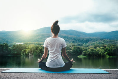 Full length of woman doing yoga against lake