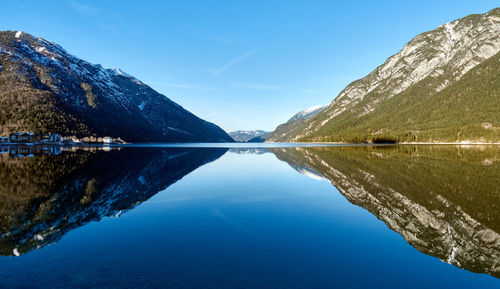 Scenic view of lake and mountains against blue sky