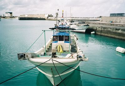 Sailboats moored in sea against sky