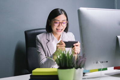 Young woman using phone while sitting on table