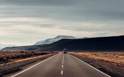 Lonely automobile going along asphalt roadway on background of amazing highlands in patagonia