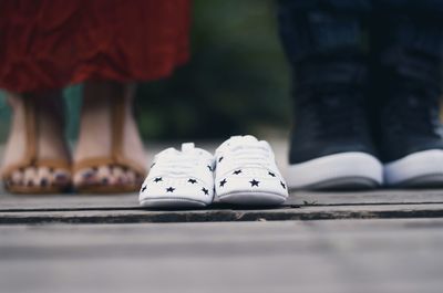 Low section of couple with baby shoes standing on road