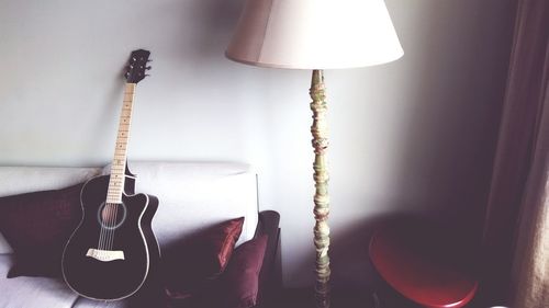 High angle view of guitar on sofa by floor lamp at home