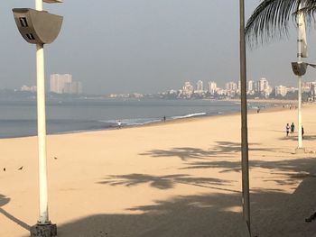 Street light on beach by city against sky