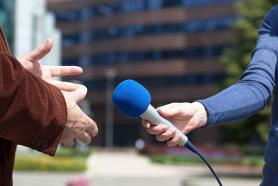 Midsection of woman taking interview of man on footpath