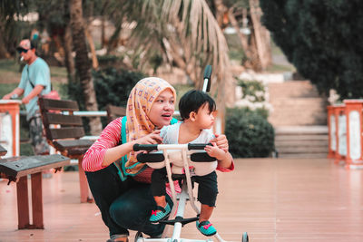 Full length of daughter with mother riding toy scooter at park