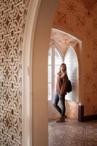 Full length of woman standing by window at home