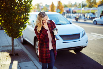 Young woman using mobile phone while standing in city