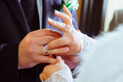 Midsection of couple wearing rings during wedding ceremony