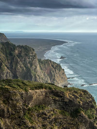 Scenic view of sea against sky with black sand beach