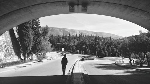 Rear view of man walking on road in city