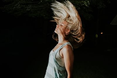 Side view of young woman with tousled hair at night