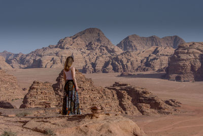 Rear view of woman on rock against sky