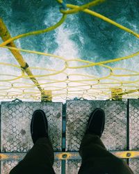 Low section of man standing on footbridge over river