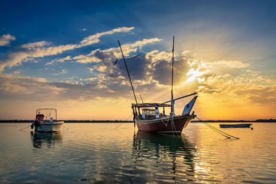 Fishing boat in sea against sky during sunset