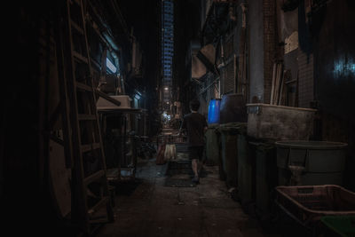 Rear view of man walking on footpath amidst buildings at night
