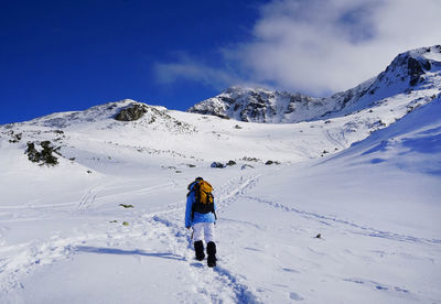 Rear view of man walking on mountain against sky