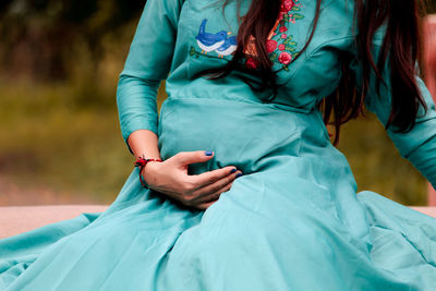 Midsection of pregnant woman while sitting outdoors