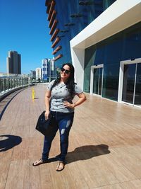 Full length portrait of young woman standing on footpath