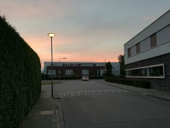 Illuminated street against sky at sunset