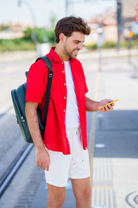 Young man using smart phone standing outdoors