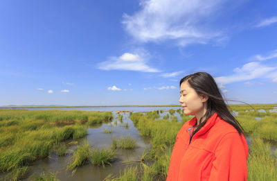 Woman standing on field against blue sky