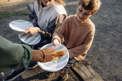 High angle view of counselor serving snacks to boy at summer camp