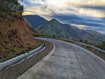 Road leading towards mountains against sky