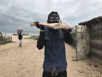 Man holding fish while standing against sky