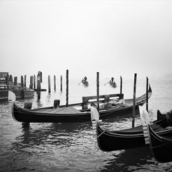 Moored boats in calm lake against clear sky