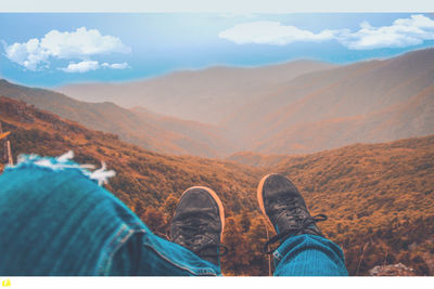 Low section of person on mountain against sky