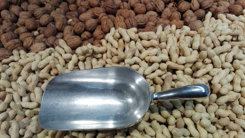 High angle view of serving scoop on peanut by walnuts for sale at market stall