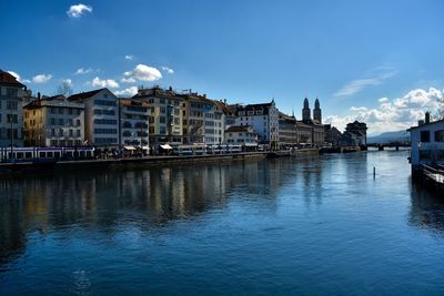 Zurich buildings by river against sky in city