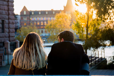 Rear view of couple sitting in city at sunset